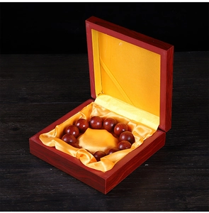 Detail of red wooden gift box with yellow silk lining containing dark wood prayer beads