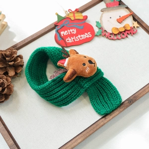 Detailed close-up of a green knitted Christmas scarf for pets with a plush elk mascot