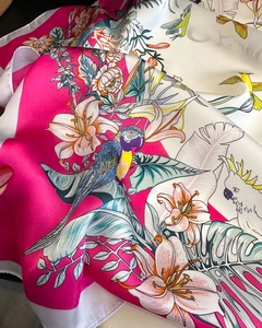 Detailed macro shot of a silk scarf featuring tropical birds and floral patterns in pink