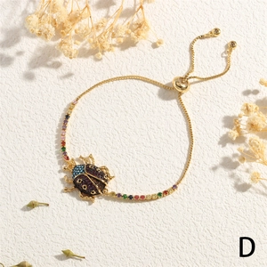 Detail of gold adjustable bracelet with colorful cubic zirconia beetle pendant and stones