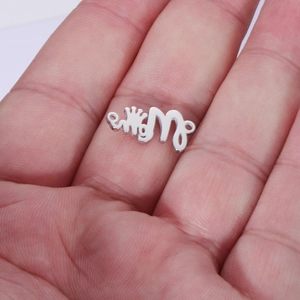 Detailed close-up of a silver MOM crown pendant connector held in hand for scale