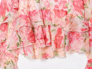 Dettaglio ravvicinato del tessuto in chiffon floreale rosa con eleganti ruches sulla camicia
