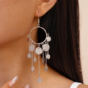 Détails de boucles d'oreilles argentées à pompons et disques martelés sur modèle