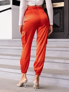 Detail of orange satin cargo pants with side pockets and elastic ankle cuffs on stairs