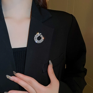 Macro detail of leaf-shaped silver brooch with white zircon on a black blazer lapel