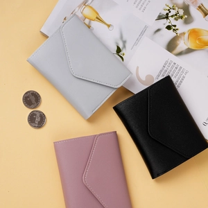 Detail view of envelope-style mini wallets in grey, black, and pink with litchi texture