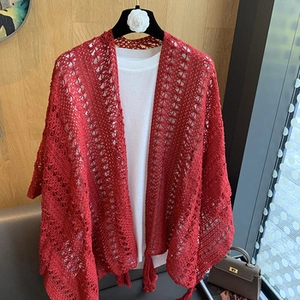 Detail of red hollow crochet knit shawl with delicate fringe and intricate patterns