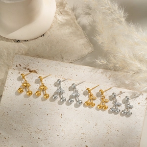 Detailed macro view of cherry-shaped drop earrings on elegant white travertine stone