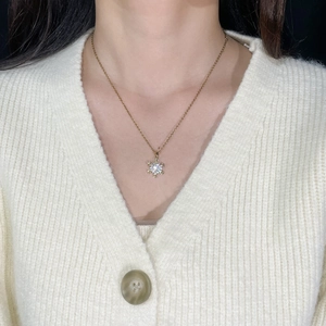 Elegant gold snowflake necklace with zircon stone worn on a soft knit sweater