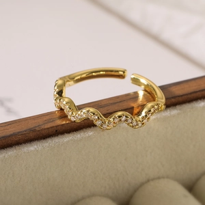 Macro shot of 18K gold plated irregular wave ring with zircon stones on beige velvet