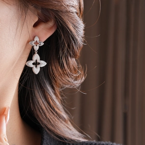 Macro detail of silver floral dangle earrings with vintage texture worn by a model