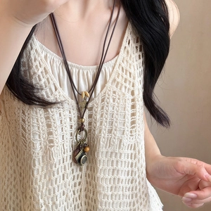 Retro wax cord necklace with wood beads and a camera pendant shown on a model