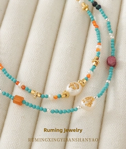 Detailed close-up of handmade necklace with colorful beads and gold-foiled pearls
