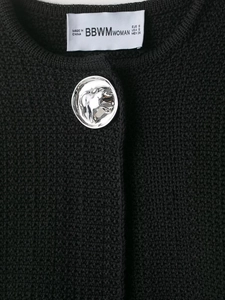 Detail of silver horse-embossed metal button on black textured knit jacket