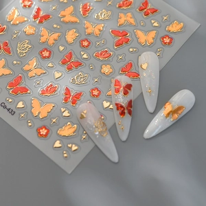 Macro detail of red and gold butterfly nail stickers with 3D embossed metallic texture
