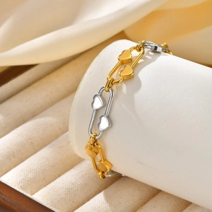 Close-up of heart-shaped links and oval metal frame on a bicolor stainless steel bracelet