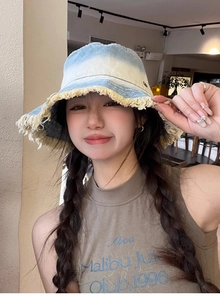 Detailed close-up of a blue and white gradient denim bucket hat with frayed edges for women