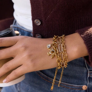 Drei goldene Armbänder im Lagen-Look mit Eulen-Anhänger und Tigerauge am Handgelenk