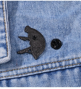 Gros plan détaillé du dos du badge en métal noir texturé avec fermoir en caoutchouc