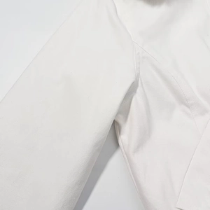 Detailed close-up showing precision stitching on a white cotton twill hooded jacket fabric