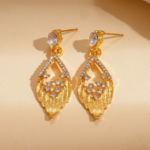 Detailed close-up of golden leaf-shaped earrings with shimmering rhinestones and texture