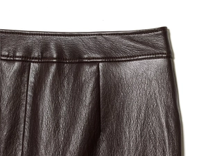 Dettaglio gonna in pelle martellata marrone scuro con cuciture in vita e texture