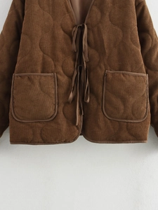 Detail van bruin corduroy gewatteerd jack met grote zakken en een striksluiting aan de taille