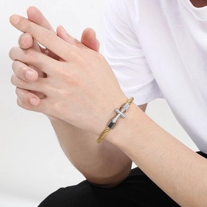 Twisted cable cuff bracelet in gold finish with silver textured cross and dark square beads