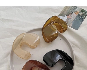 U-shaped hair claws in amber, beige, black and brown colors on a ceramic tray