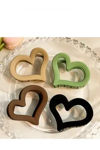 Detailed view of four matte heart-shaped hair claw clips in assorted autumn colors