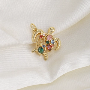 Macro shot of gold turtle pendant with colorful zircon stones on white silk fabric