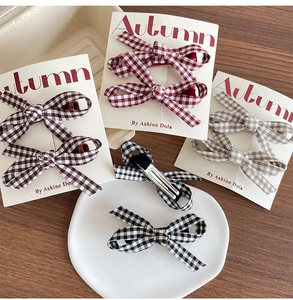 Flat lay of plaid bow hair clips in burgundy, brown and khaki on a display card