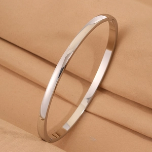 Macro detail of polished stainless steel curved bangle on soft beige fabric
