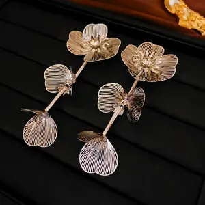 Boucles d'oreilles pendantes fleurs dorées avec pétales ajourés sur velours noir