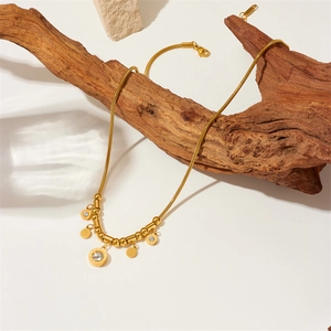 Golden titanium steel snake chain necklace with round pendants and crystals on wood