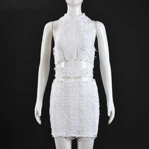 Dettaglio del set bianco a due pezzi con bordi sfrangiati e top corto con scollo all'americana
