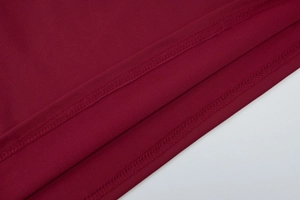 Detailed macro view of dark red knit fabric with durable double-stitch hem edge finish