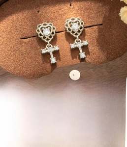 Detail view of coffee gold heart and cross stud earrings with sparkling zircon stones