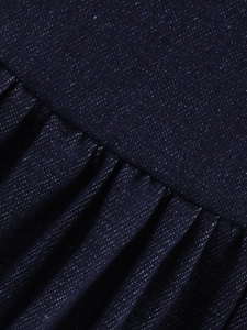 Vue macro détaillée de la texture denim bleu foncé et du design froncé de la robe