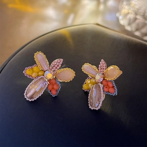 Vue macro de boucles d'oreilles fleuries perlées avec strass brillant au centre