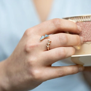 Détail d'une bague papillon dorée aux ailes bleues et cristaux portée par un mannequin