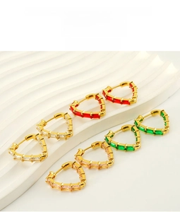 Detailed shot of gold heart earrings set with colorful zircon crystals on white texture