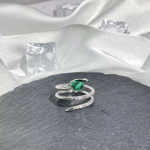 Detailed macro of a silver snake ring with green pear-shaped gemstone and scale texture