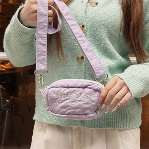 Close-up of lavender crossbody bag featuring delicate white bow embroidery and silver hardware