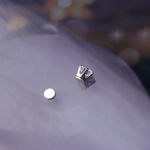 Detailed view of silver magnetic ear clip with clear cubic zirconia on reflective surface