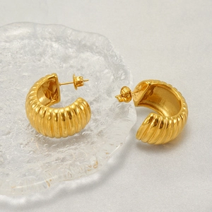 Fashionable golden C-shaped stainless steel earrings with textured stripes on fabric