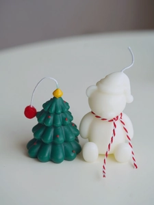 Detailed close-up of handmade green Christmas tree and white bear festive candle set