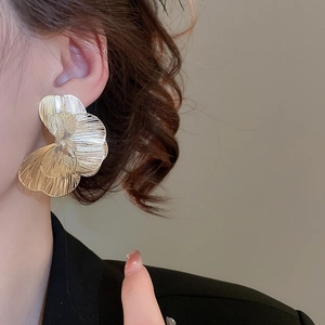 Gros plan de boucles d'oreilles fleurs dorées avec texture en métal brossé
