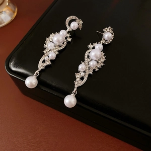 Close-up of wheat ear shaped silver earrings with pearls and crystals on a black box