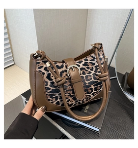 Detail of leopard print shoulder bag featuring metal buckle and knotted handle design